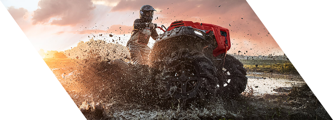 ATV rider splashing through mud on rugged terrain